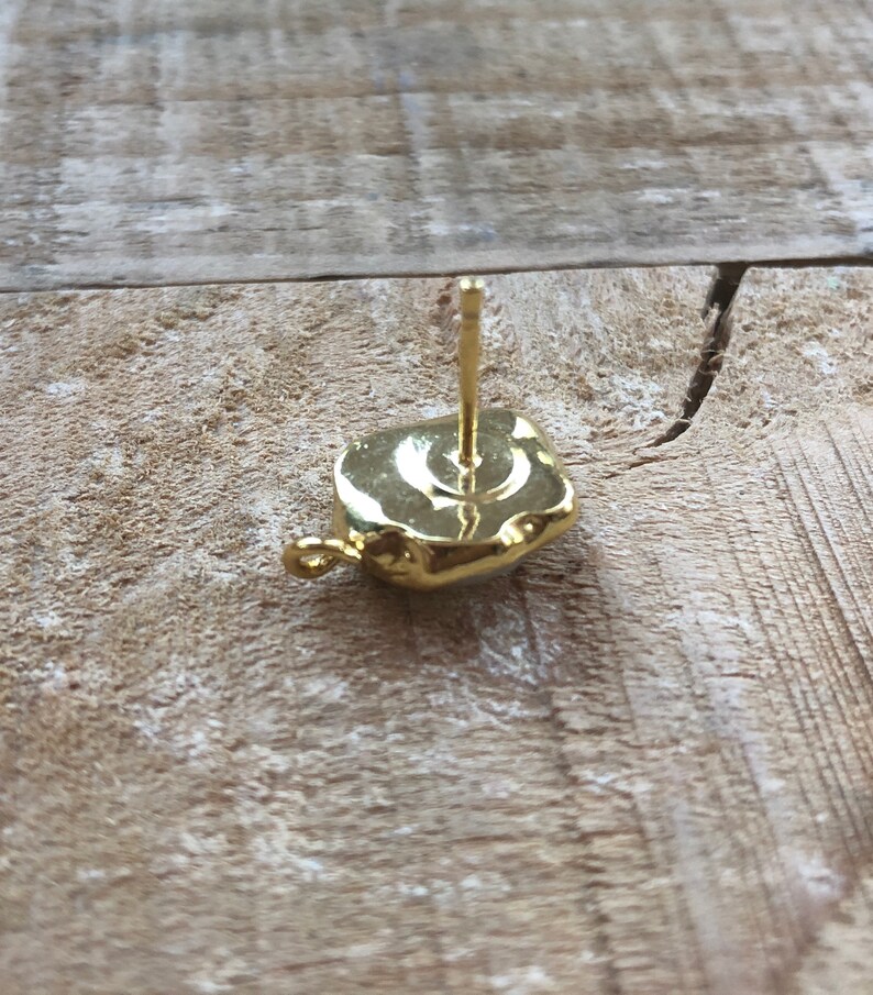 May include: Gold earring with a square-shaped stone. The earring has a post and a small loop on the back.