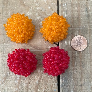 May include: Four small round beaded ornaments, two are orange and two are red. The ornaments are about the size of a UK penny.