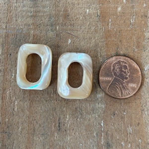 以下が含まれることがあります： 中央に穴が開いた、オフホワイトの貝殻のような長方形のビーズが2つ。ビーズは1円玉くらいの大きさです。