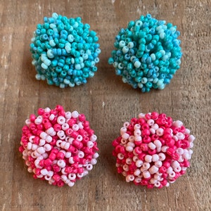 May include: Four round beaded earrings, two are pink and white and two are blue and white.