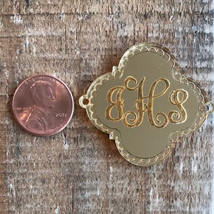 Puede incluir: Encanto de monograma de iniciales de color dorado con un borde festoneado decorativo. Las iniciales "EHS" están grabadas en escritura cursiva.