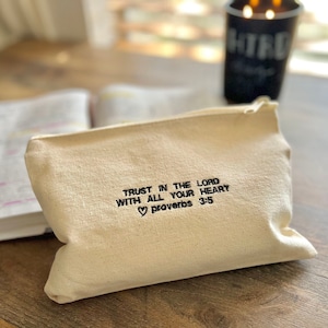 May include: A beige canvas zippered pouch with the text "Trust in the Lord with all your heart ♥ Proverbs 3:5" embroidered in black.