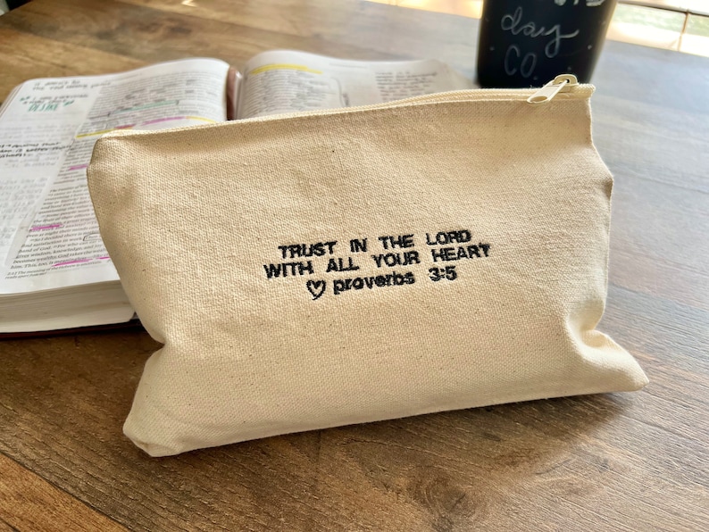 Peut inclure: Une pochette zipp&eacute;e en toile beige avec le texte "Trust in the Lord with all your heart Proverbs 3:5" brod&eacute; en noir.