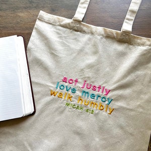 May include: A white canvas tote bag with the words "act justly, love mercy, walk humbly, Micah 6:8" embroidered in colorful thread.