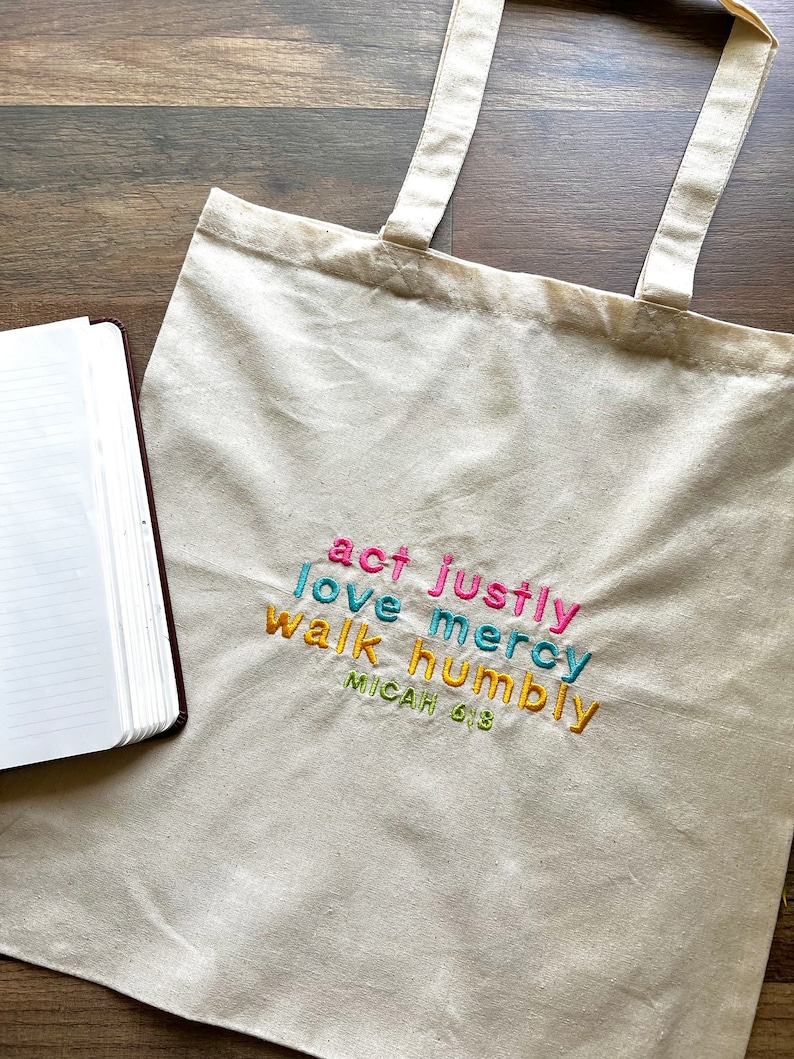 May include: A white canvas tote bag with the words "act justly, love mercy, walk humbly, Micah 6:8" embroidered in colorful thread.