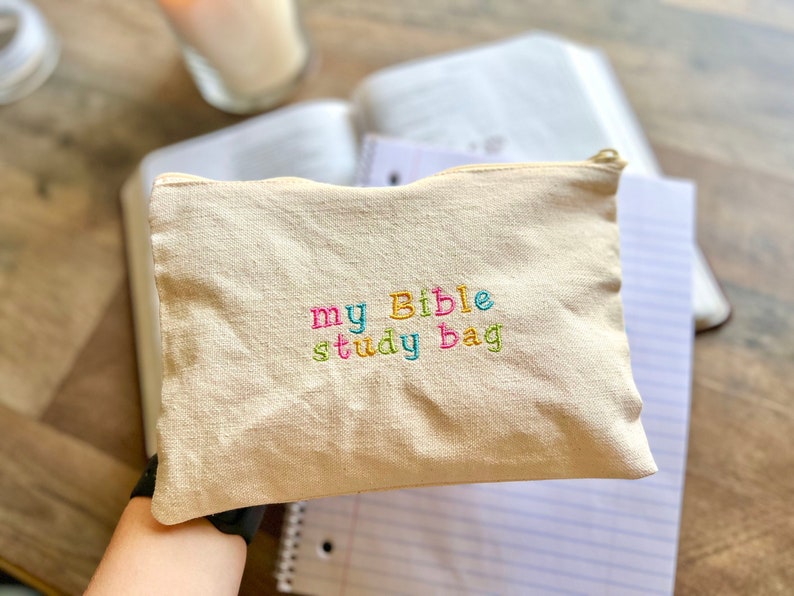 May include: A beige canvas bag with a zipper closure. The bag has colorful embroidery that reads "my Bible study bag".