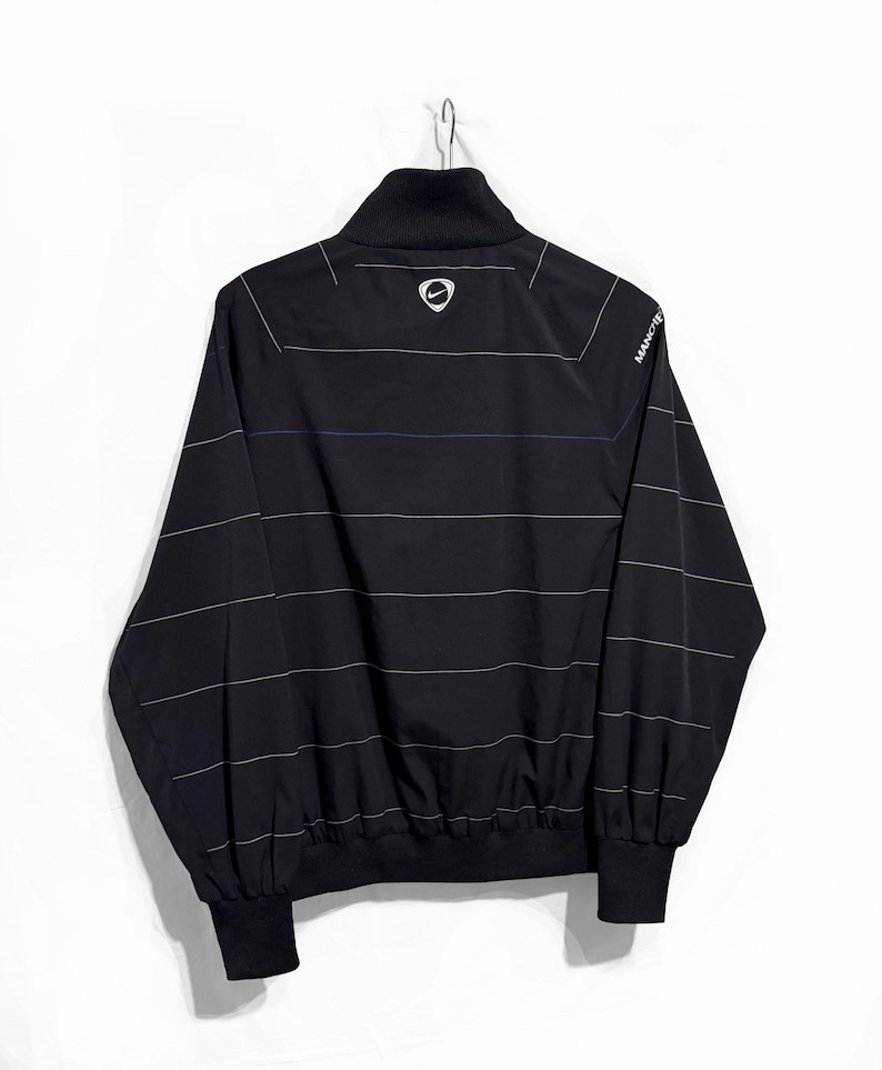 K&ouml;nnte beinhalten: Eine wei&szlig;e Keramik-Tasse mit schwarzem Henkel und dem Text "But First, Coffee" in schwarzer, fetter Schrift. Die Tasse steht auf einer wei&szlig;en Oberfl&auml;che.