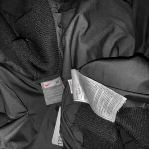 K&ouml;nnte beinhalten: Eine wei&szlig;e Keramik-Tasse mit schwarzem Henkel und dem Text "But First, Coffee" in schwarzer, handschriftlicher Schrift. Die Tasse steht auf einer wei&szlig;en Oberfl&auml;che.