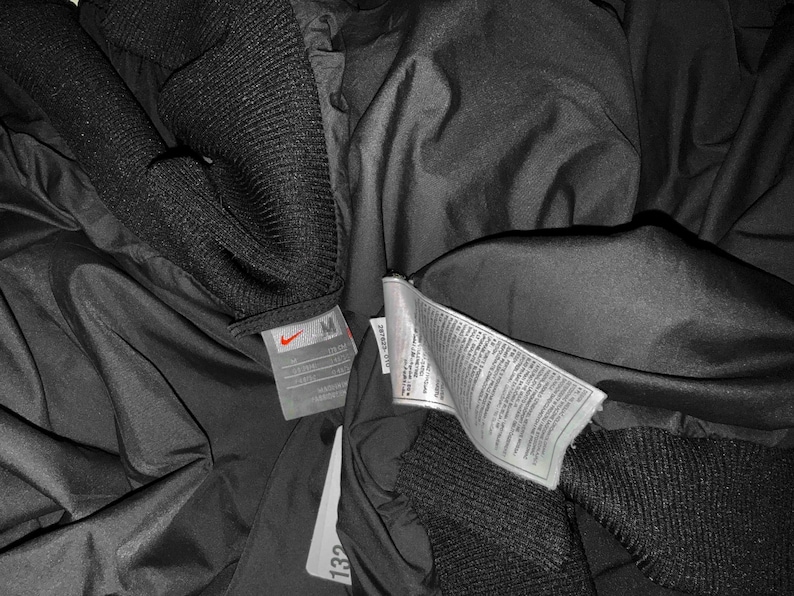 K&ouml;nnte beinhalten: Eine wei&szlig;e Keramik-Tasse mit schwarzem Henkel und dem Text "But First, Coffee" in schwarzer, handschriftlicher Schrift. Die Tasse steht auf einer wei&szlig;en Oberfl&auml;che.