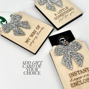 Pode incluir: Porta-cartões de presente de madeira com laços de glitter prateado. Um diz "MY WAY OF saying thanks", outro "A LITTLE SOMETHING just for you" e um terceiro "INSTANT happiness ENCLOSED".