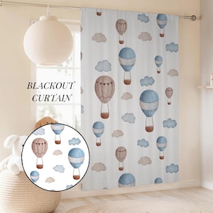 Puede incluir: Cortina opaca blanca con un patrón repetido de globos aerostáticos de acuarela en tonos azules, marrones y beige, junto con nubes esponjosas. El texto "BLACKOUT CURTAIN" está impreso en el lado izquierdo.