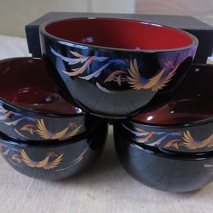 May include: Set of four black lacquer bowls with red interiors and gold phoenix designs. The bowls are stacked on top of each other.