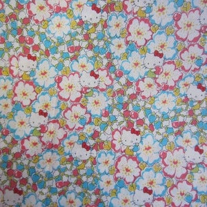 May include: A white fabric with a repeating pattern of pink and blue flowers and a cartoon character with a red bow.