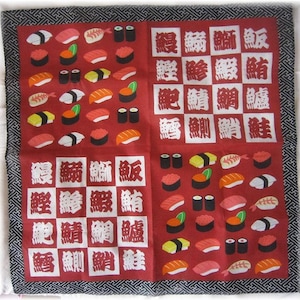 May include: Red fabric with a black border featuring a pattern of sushi and Japanese characters. The characters are in white and read "Maguro" (tuna), "Sake" (salmon), "Tai" (sea bream), and "Ebi" (shrimp).