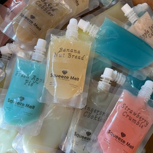 Puede incluir: Una variedad de bolsas coloridas con diferentes sabores de cera de soja derretida. Las bolsas est&aacute;n etiquetadas con nombres como "Baked Cobbler", "Banana Nut Bread", "Fresh Apple Pie", "Ginger Snap Cookies", "Strawberry Crumble" y "Squeeze Melt".