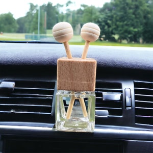 A wooden car vent diffuser clipped to a car air vent, dispersing fragrance through reed sticks. The sleek design complements the car’s interior.