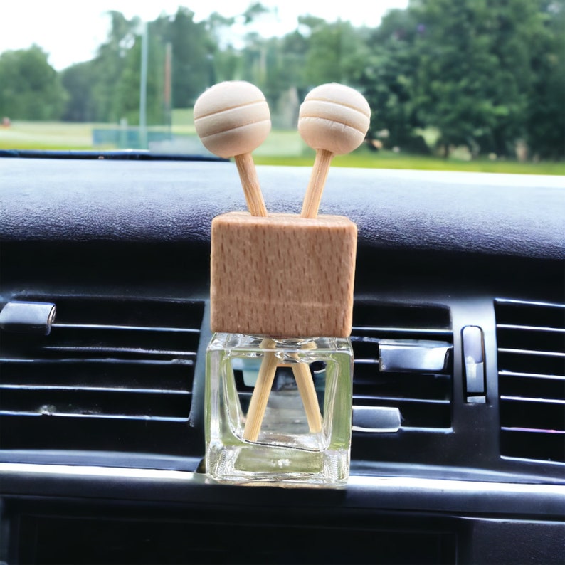 A wooden car vent diffuser clipped to a car air vent, dispersing fragrance through reed sticks. The sleek design complements the car’s interior.