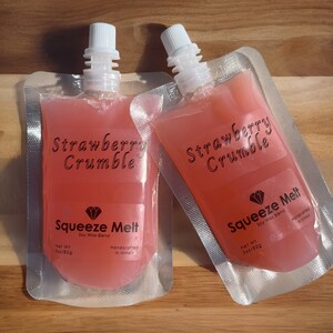 Puede incluir: Dos bolsas de cera de soja con aroma a crumble de fresa. Cada bolsa est&aacute; etiquetada con "Strawberry Crumble" y "Squeeze Melt Soy Wax Blend" con un logotipo de diamante. Las bolsas son de 3 oz (85g) y est&aacute;n hechas a mano en Illinois.