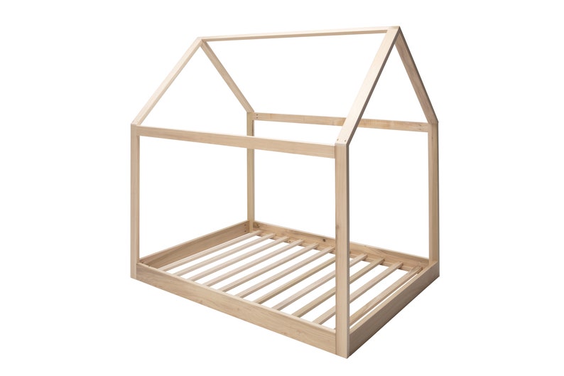 May include: A light-colored wooden bed frame shaped like a house, featuring a rectangular base with horizontal slats and an open-frame roof structure constructed from four vertical posts and angled beams meeting at a central peak.