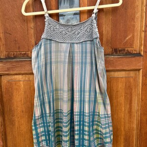 May include: A sleeveless, plaid top with a crocheted neckline. The top is in shades of blue, green, pink, and white.