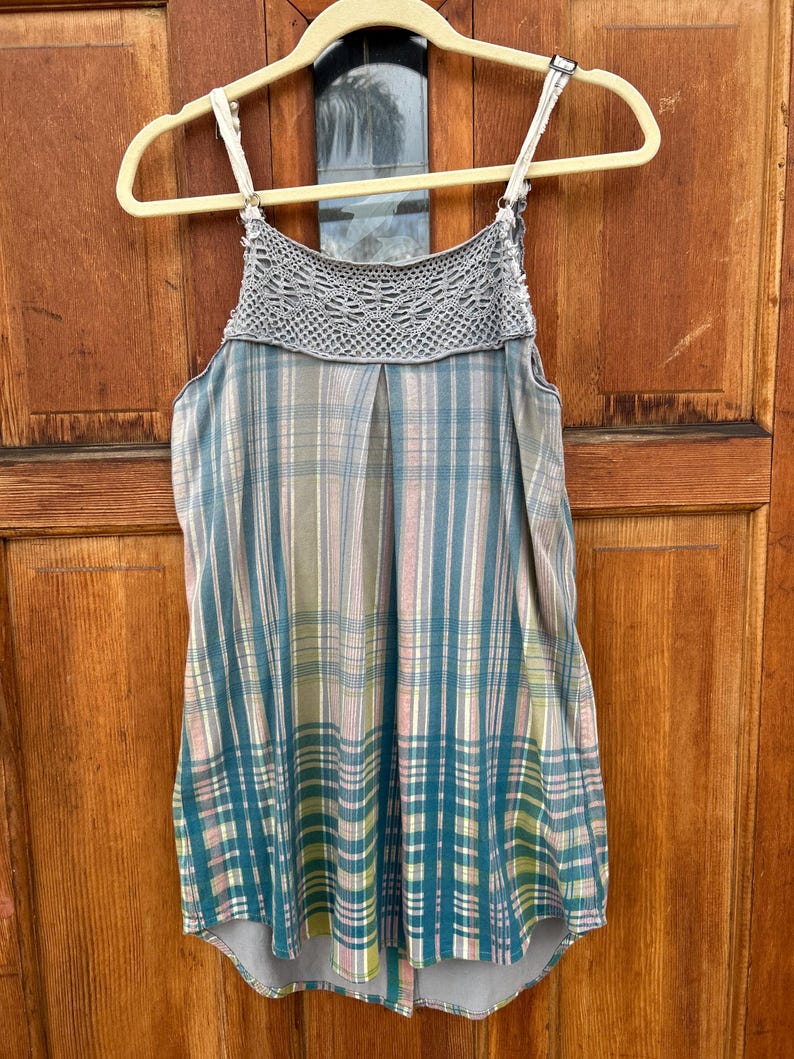 May include: A sleeveless, plaid top with a crocheted neckline. The top is in shades of blue, green, pink, and white.