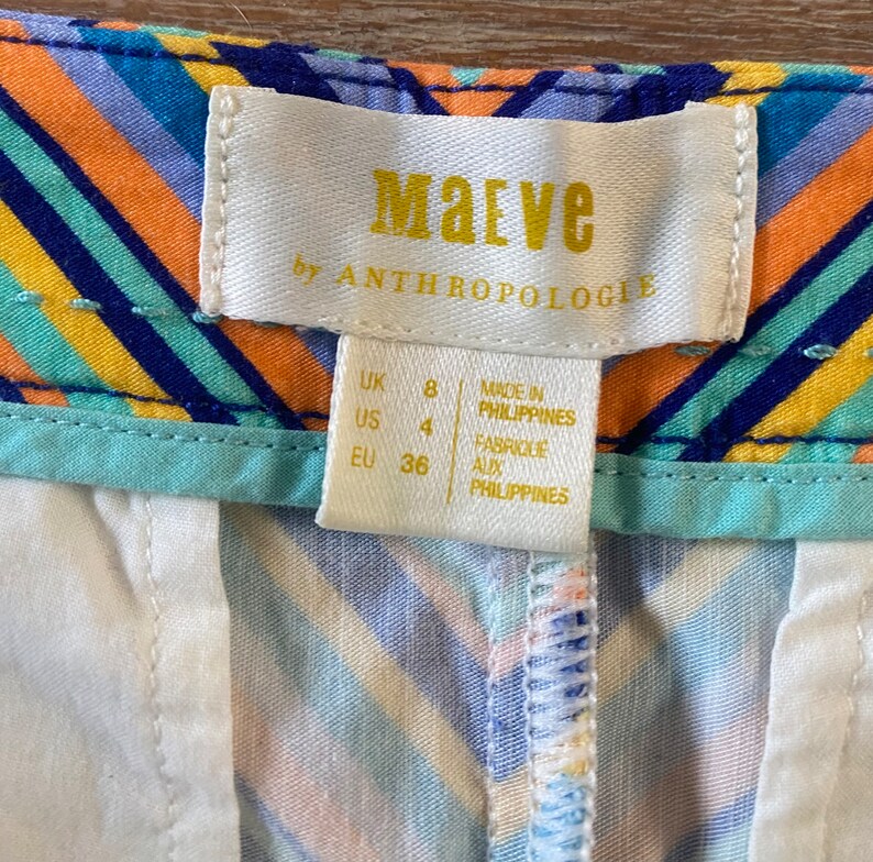 May include: A white tag with the text "Maeve by Anthropologie" in gold lettering. The tag also includes size information: UK 8, US 4, EU 36. The tag states "Made in Philippines" and "Fabriqu&eacute; aux Philippines".