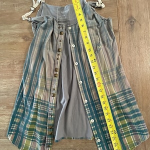 May include: A gray and blue plaid sleeveless top with a button-up front and studded accents. The top is made of a soft, lightweight fabric and has a relaxed fit.