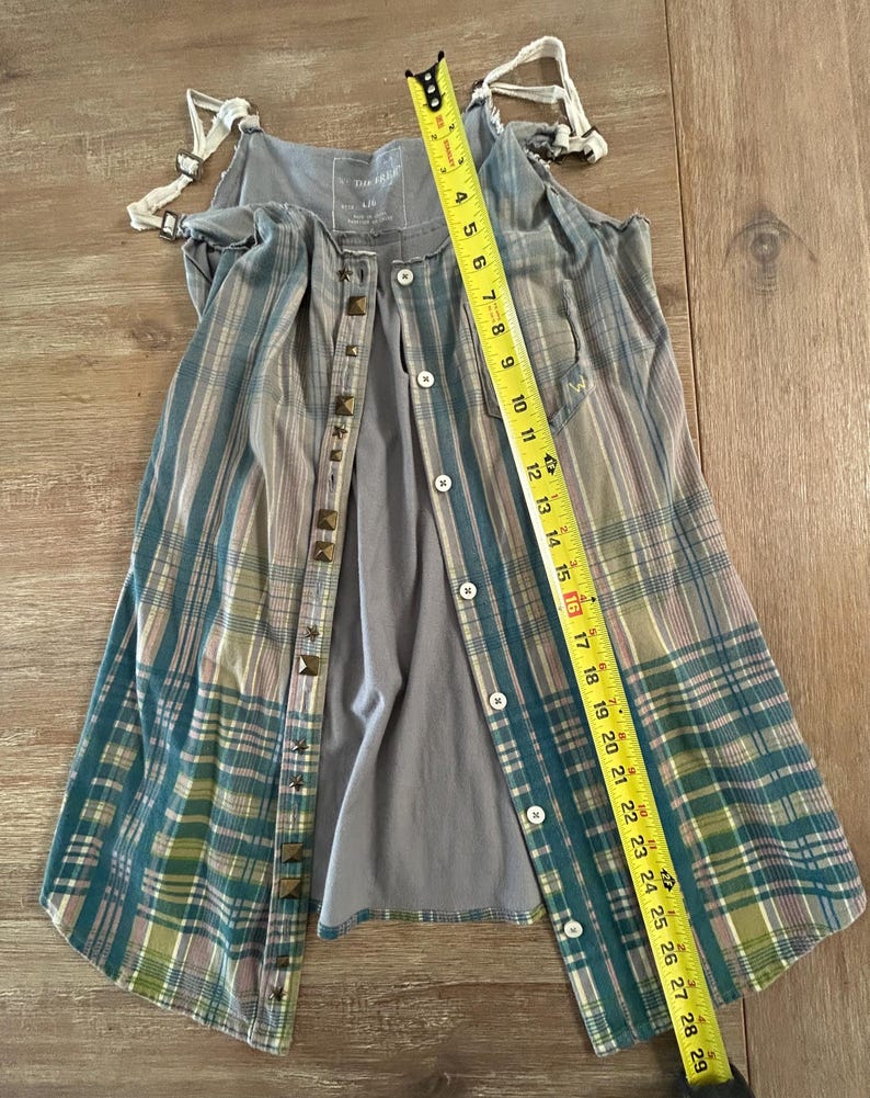 May include: A gray and blue plaid sleeveless top with a button-up front and studded accents. The top is made of a soft, lightweight fabric and has a relaxed fit.