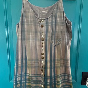 May include: A blue and gray plaid sleeveless dress with a button front and brown studded accents. The dress has a Free People tag with the size L/G.