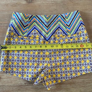 May include: Yellow, blue, and orange patterned shorts with a chevron pattern at the waistband. The shorts are made of a lightweight fabric and have a relaxed fit.