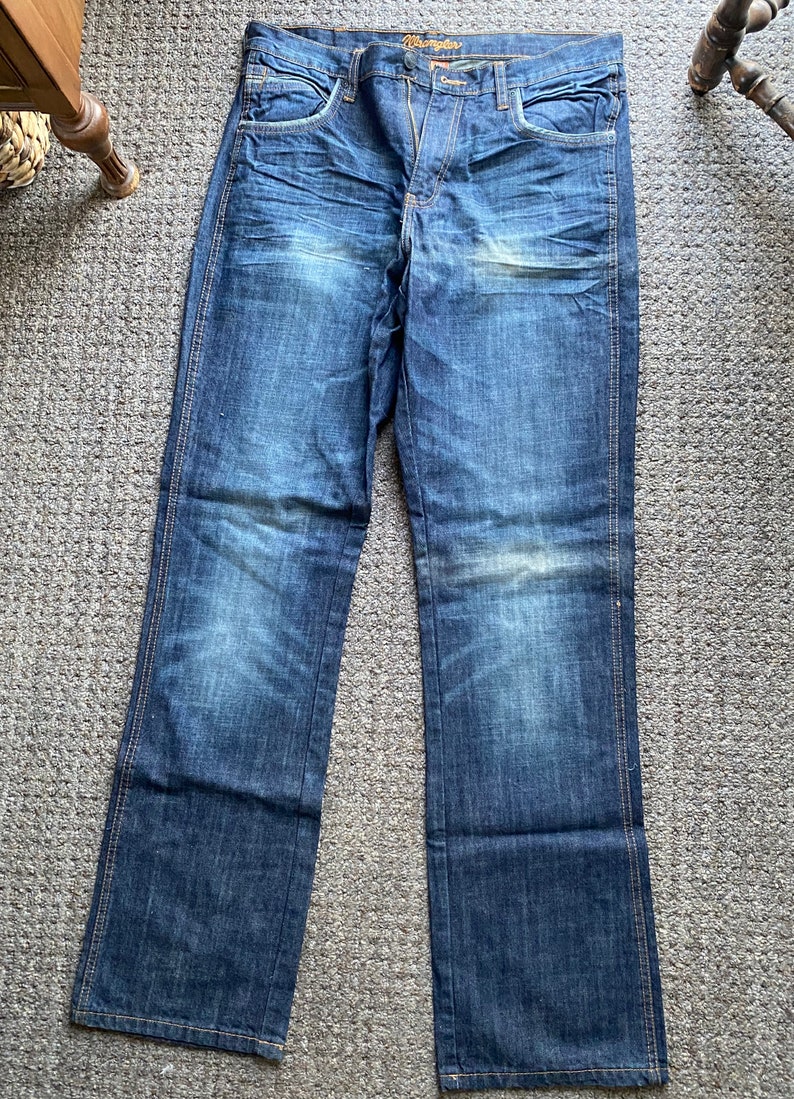 K&ouml;nnte beinhalten: Eine blaue Jeanshose mit Bootcut-Bein&ouml;ffnung. Die Jeans hat einen ausgewaschenen Look und ist von Wrangler.