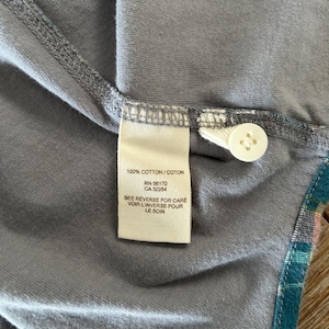 May include: A white tag with black text that reads "100% COTTON/COTON", "RN 66170", "CA 32054", "SEE REVERSE FOR CARE", "VOIR L'INVERSE POUR", "LE SOIN".