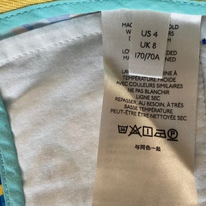 May include: White care label with black text and symbols. The text includes "US 4", "UK 8", "170/70A", "Temperature Froide", "Ne Pas Blanchir", "Ligne Sec", "Repasser, Au Besoin, A Tres Basse Temperature", "Peut-&Ecirc;tre &Ecirc;tre Nettoye&eacute; Sec", and "Avec Couleurs Similaires". The label also includes a washing instruction symbol.