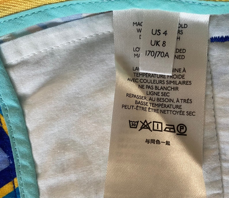 May include: White care label with black text and symbols. The text includes "US 4", "UK 8", "170/70A", "Temperature Froide", "Ne Pas Blanchir", "Ligne Sec", "Repasser, Au Besoin, A Tres Basse Temperature", "Peut-&Ecirc;tre &Ecirc;tre Nettoye&eacute; Sec", and "Avec Couleurs Similaires". The label also includes a washing instruction symbol.