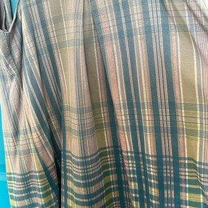 May include: A sleeveless top with a plaid pattern in shades of brown, green, and pink. The top has a crocheted trim at the neckline.