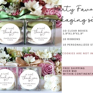 May include: A set of 10 clear favor boxes with white ribbons and personalized stickers. The boxes are 1.9 inches by 1.9 inches by 1.9 inches. The stickers say "a sweet thank you" with a heart and space for a name and date.  The boxes are shown with macarons and cookies, but cookies are not included.