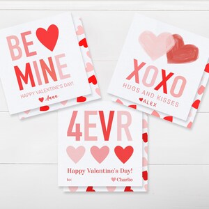 May include: Three Valentine's Day cards with red and pink hearts and text. One card says "BE MINE" and "Happy Valentine's Day!" with a name. Another says "XOXO HUGS AND KISSES" with a name. The third says "4EVR" and "Happy Valentine's Day!" with a name.