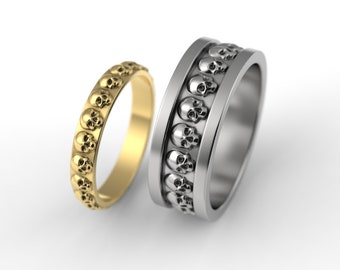 May include: Two wedding bands with a skull design. One band is gold and the other is silver.