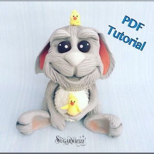 May include: A gray bunny with red ears and big eyes is holding a yellow chick in its arms. Another yellow chick is perched on top of the bunny's head. The bunny is sitting on a light blue background. The text "PDF Tutorial" is written in blue letters on the top right corner of the image.