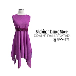 May include: A sleeveless, shimmering purple dance dress with a sequined belt. The dress has an asymmetrical hemline and is displayed on a mannequin. Text on the right reads "Shekinah Dance Store PRAISE DANCEWEAR By Dalia SM."