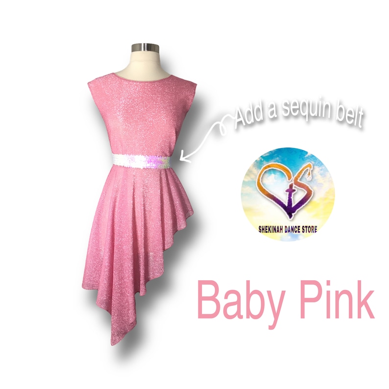 May include: A baby pink dance dress with a sequined belt. The dress has a high neckline and a short, cap sleeve. The skirt is asymmetrical and flows to the side. The dress is on a mannequin. The text "Add a sequin belt" is written on the image. The text "Shekinah Dance Store" is written on a circle with a heart and cross design.