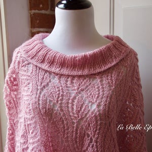 May include: A light pink knitted poncho featuring an intricate openwork leaf pattern and a wide ribbed collar. The garment displays a delicate texture throughout the knit. The text La Belle Epoque Knits is visible in the lower right corner.