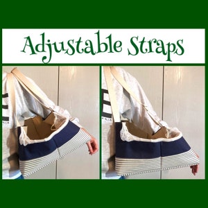 Puede incluir: Un transportín para mascotas a rayas azul marino y blanco con correas beige ajustables. El transportín tiene una parte superior de malla y se lleva sobre el hombro. El texto "Adjustable Straps" está en verde.