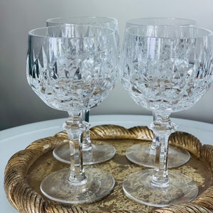 Könnte beinhalten: Vier klare Weingläser aus Glas mit geschnittenem Kristallmuster, die auf einem goldenen Tablett mit einem seilartigen Rand stehen.