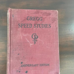 Könnte beinhalten: Ein rotes Hardcover-Buch mit dem Titel "Gregg Speed Studies Anniversary Edition" und einem schwarz-weißen Logo auf dem Einband.