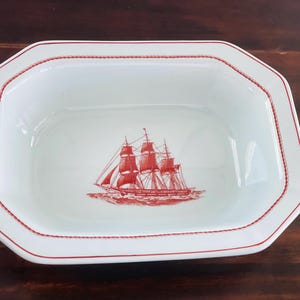 Puede incluir: Plato de cerámica blanco con una ilustración de barco náutico rojo. El plato tiene forma rectangular con un borde octogonal y un borde rojo en forma de cuerda. Un diseño clásico para servir alimentos.