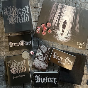 May include: A tabletop role-playing game set called "Oldest Child: Forbidden Histories". The set includes a black box with the game title, a black and white illustration of a forest, a black and white illustration of a house, a black card with the text "Year One Story", a black card with the text "Item/Effect", a black card with the text "History 1", a black pouch, and red dice.