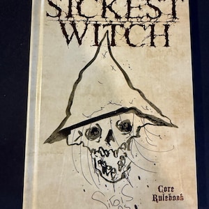 Puede incluir: Un libro titulado "Sickest Witch" con una ilustración de una calavera con un sombrero de bruja. La portada es de color blanquecino con texto e ilustraciones en marrón oscuro. También se ven las palabras "Core Rulebook".