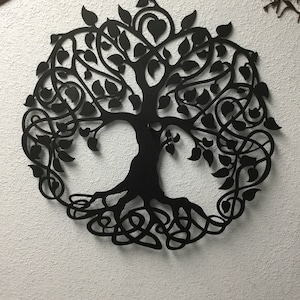 May include: Black metal wall art depicting a tree of life with intricate branches, leaves, and roots. The design is circular and features a Celtic knot pattern.