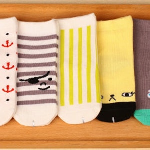 May include: Set of six colorful socks with different patterns. The socks feature a variety of designs, including anchors, stripes, a pirate eye patch, a cat face, and an ice cream cone.